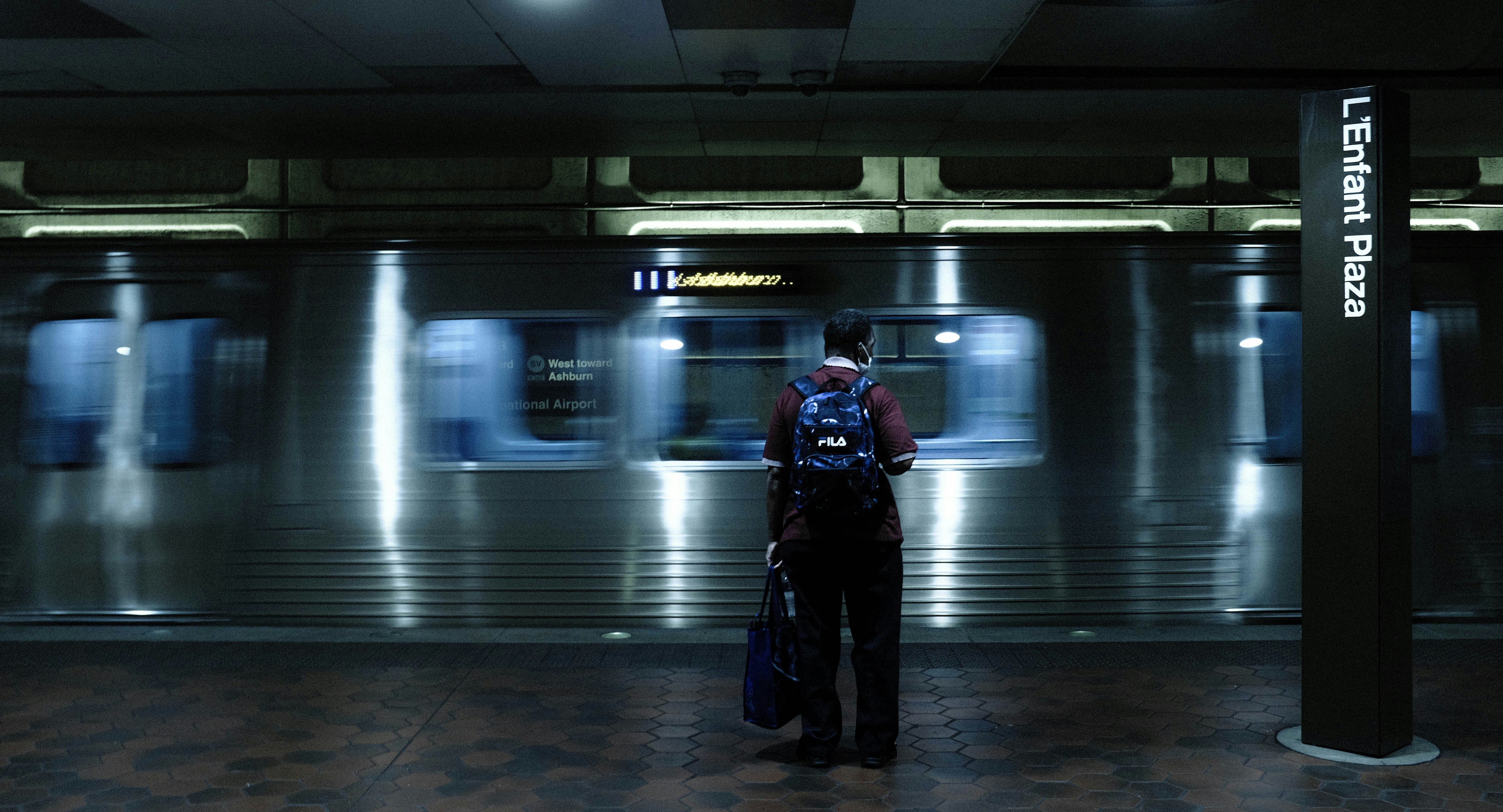 A man standing in a train station holding a suitcase