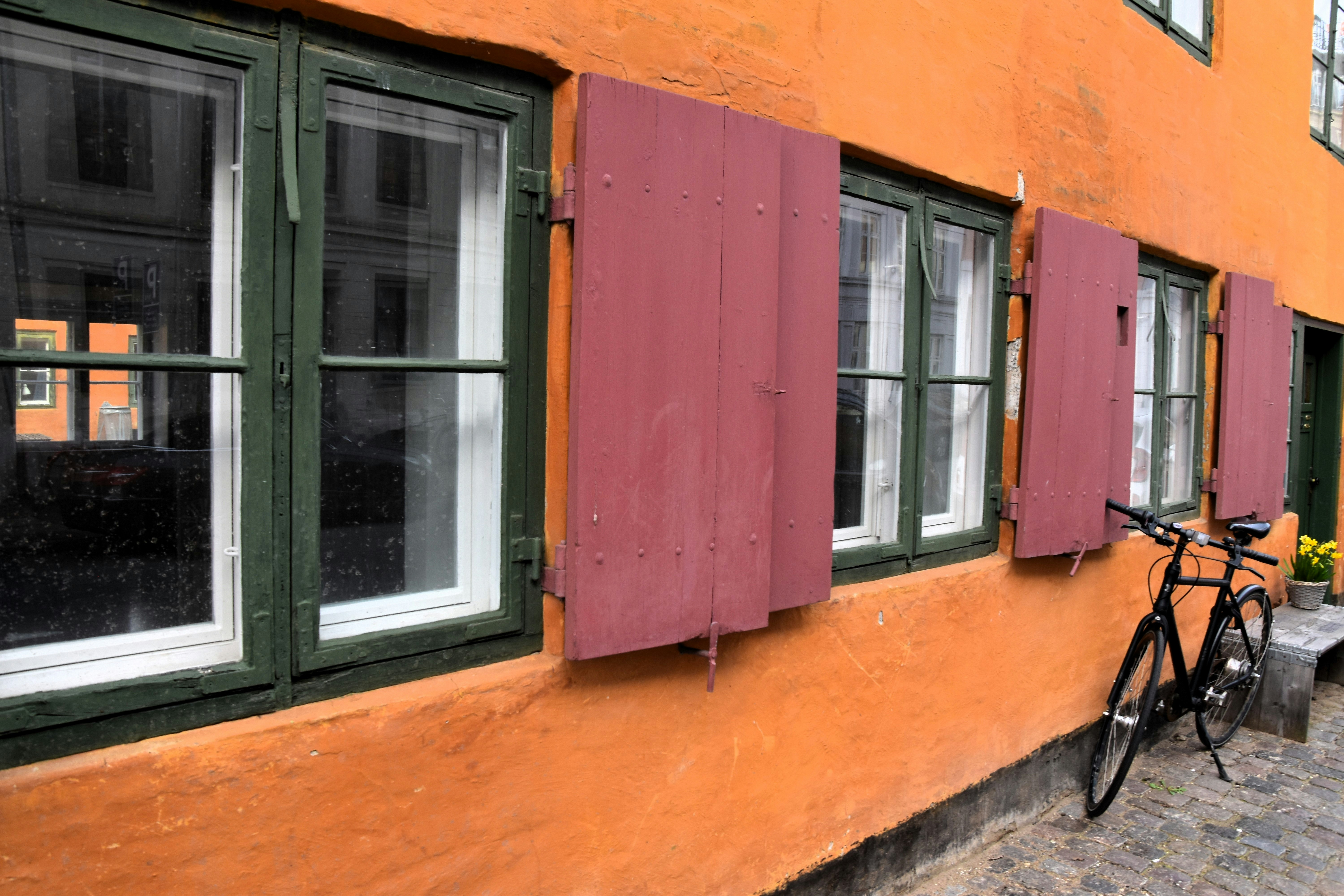 A bike parked in front of a building with red shutters