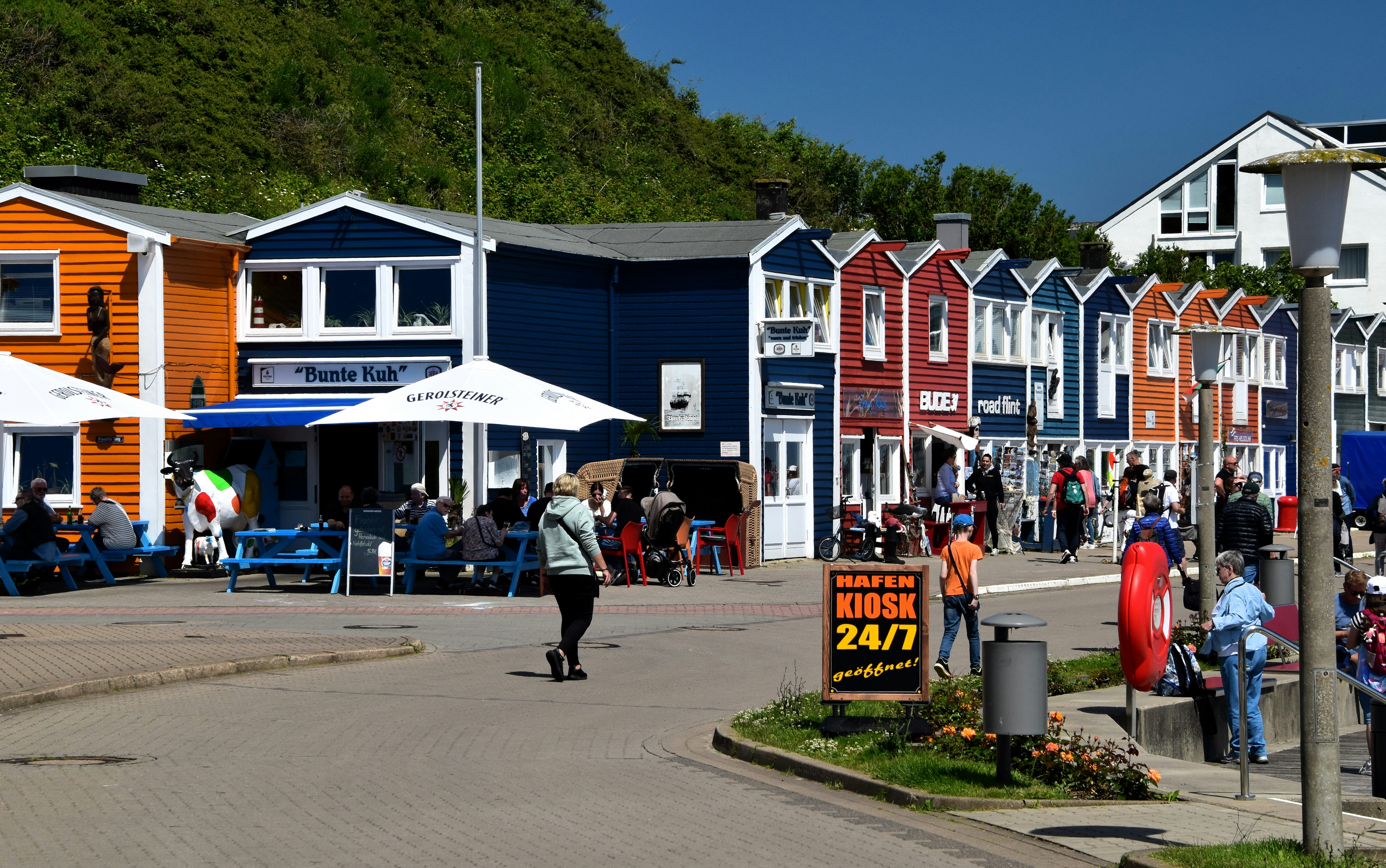 A group of people walking down a street next to colorful houses