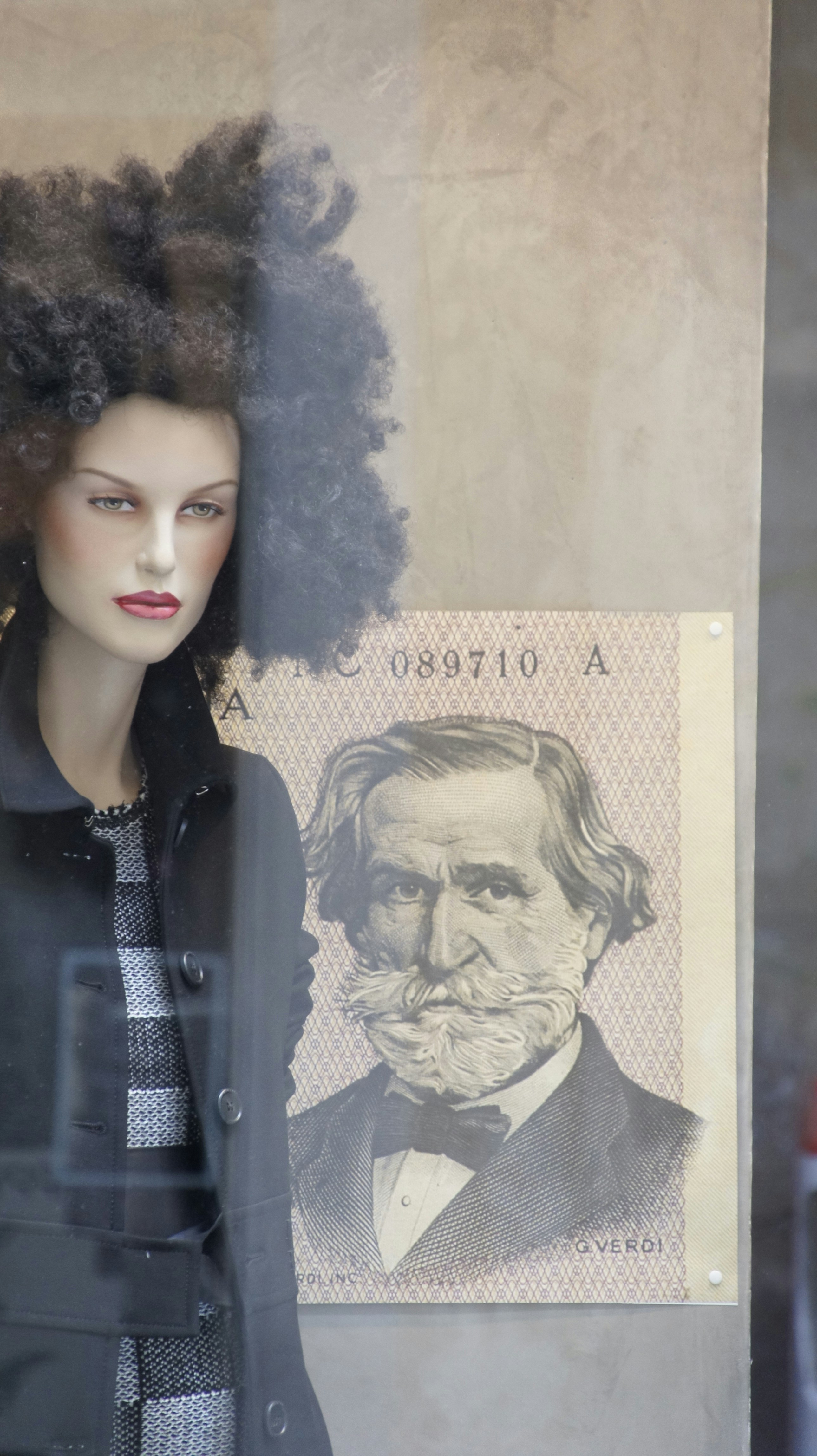 A mannequin in a window with a portrait of a man