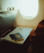 An airplane seat with a tray and a passport on it