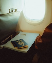 An airplane seat with a tray and a passport on it