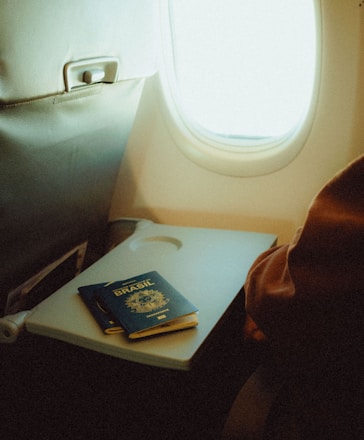 An airplane seat with a tray and a passport on it
