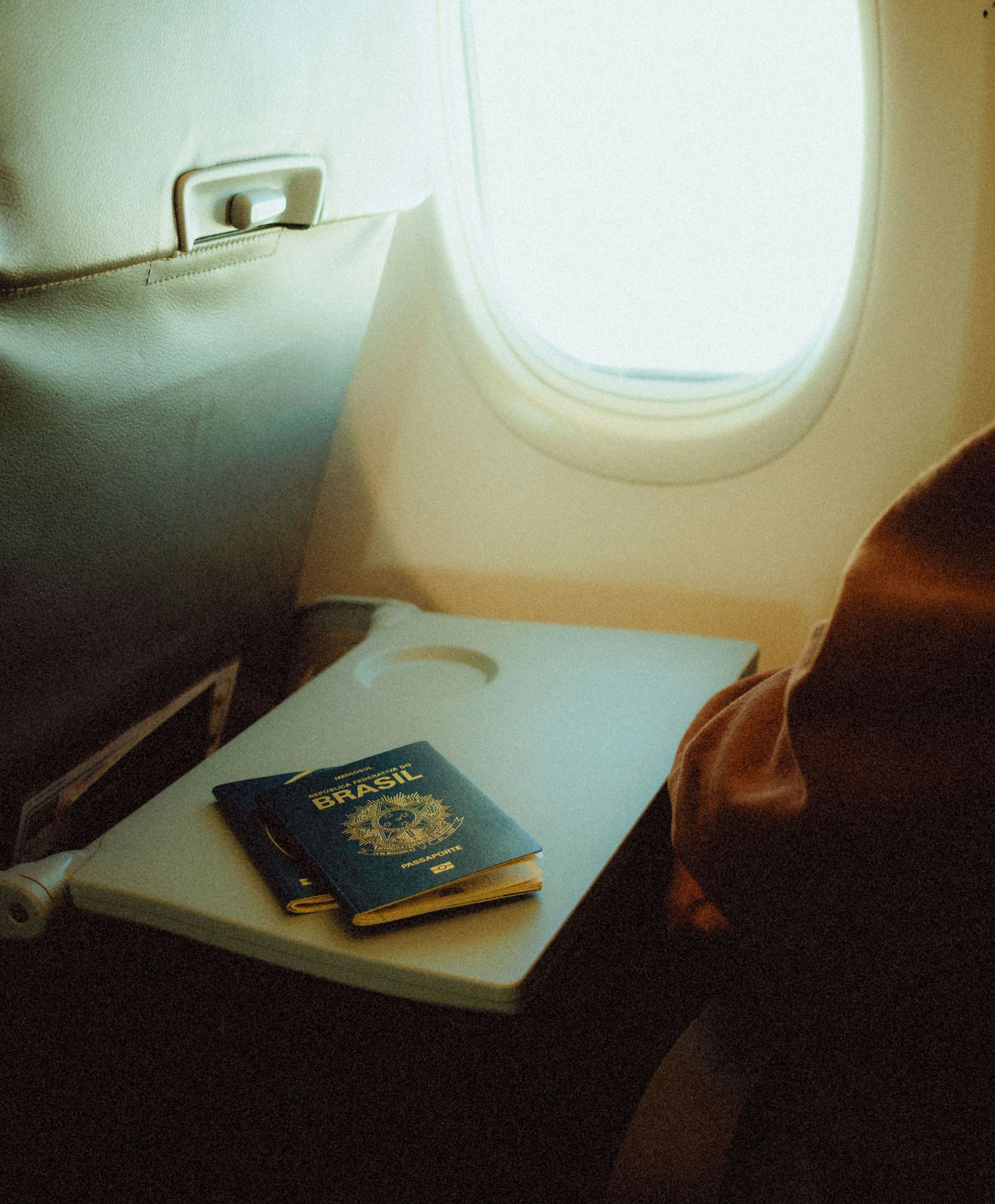 An airplane seat with a tray and a passport on it