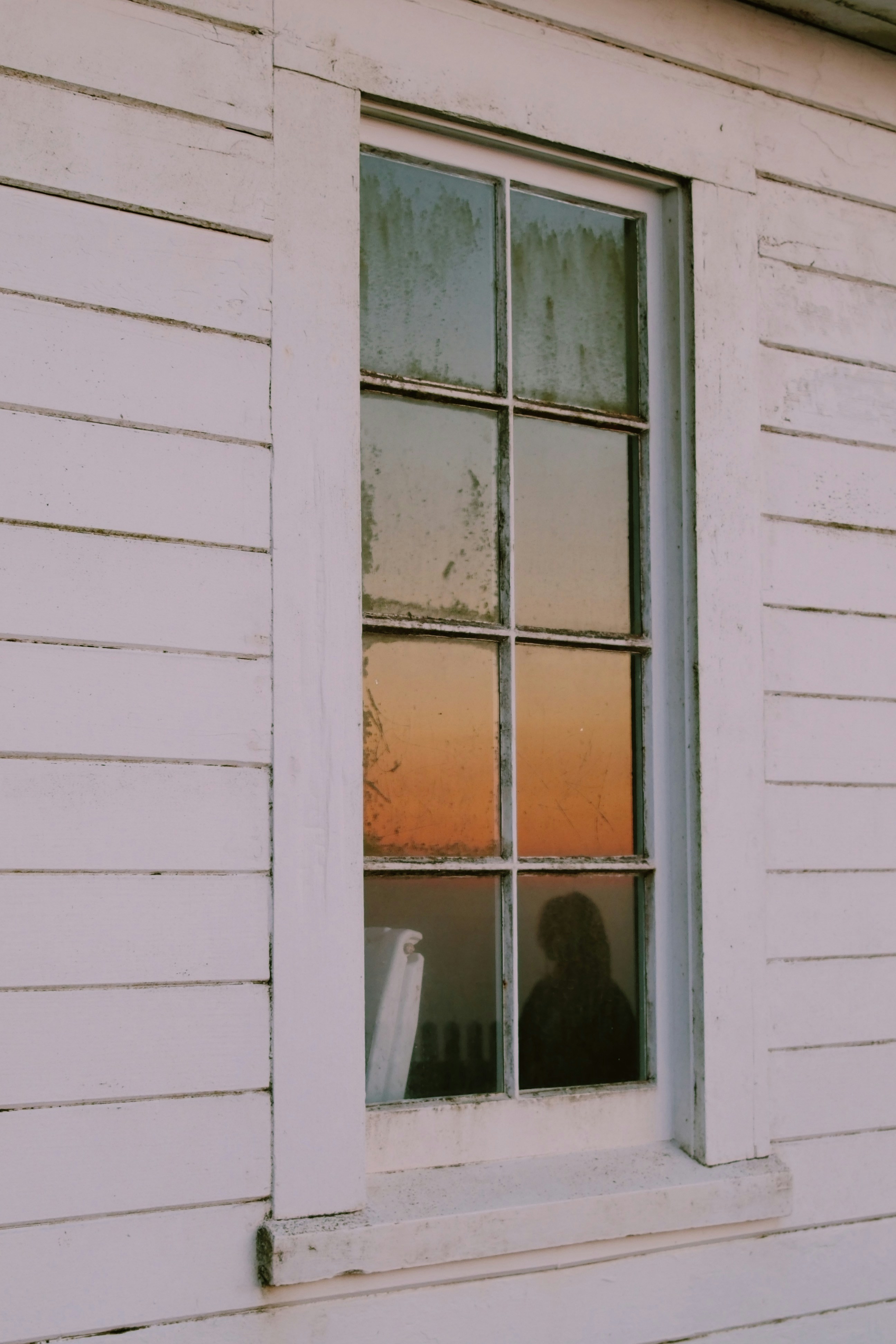 A person looking out of a window at the sunset