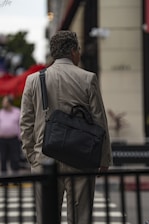 A man walking across a street carrying a black bag