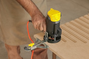 A man using a router to cut a piece of wood
