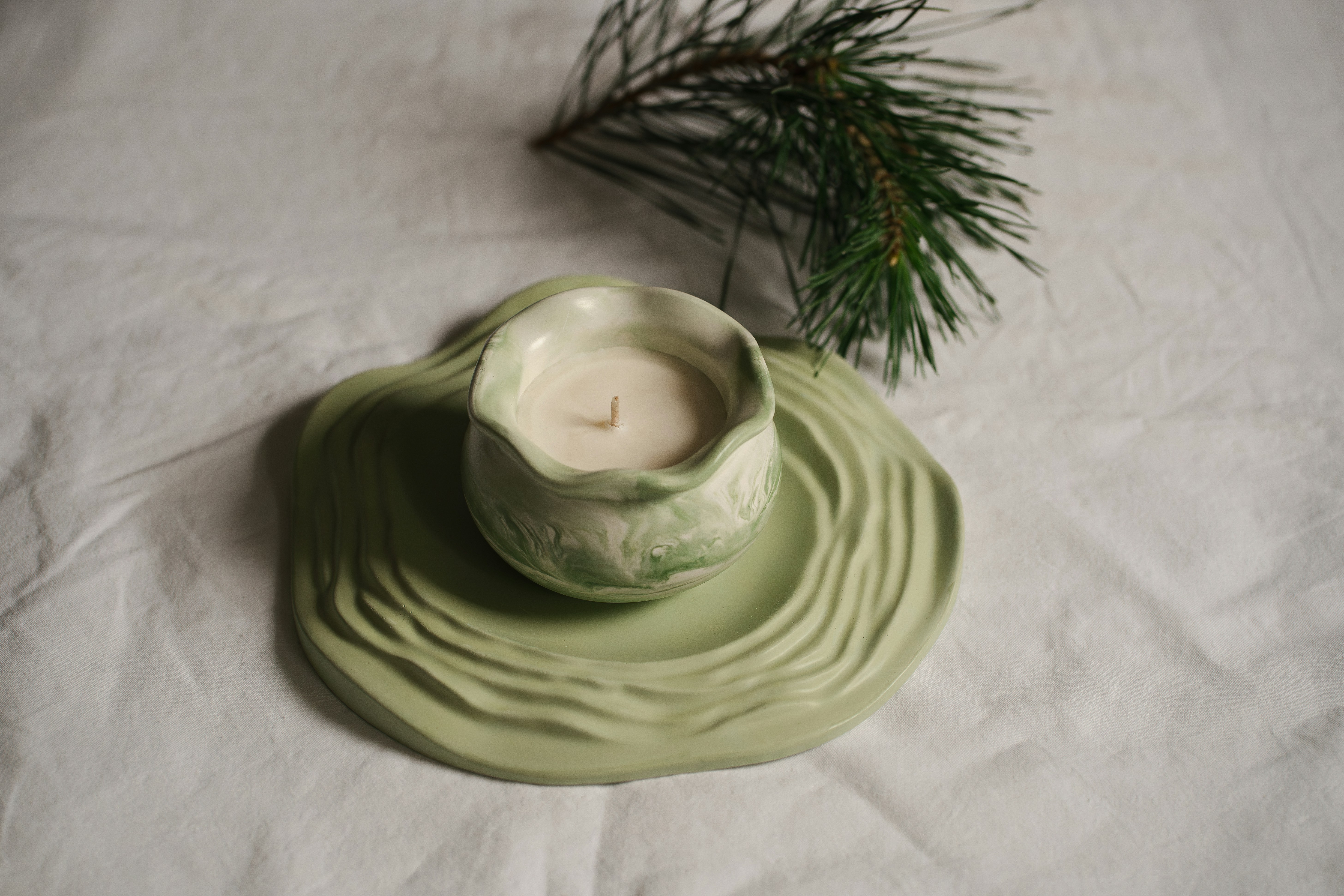 A green candle sits on top of a white cloth