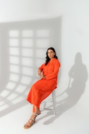 A woman in an orange dress sitting on a chair