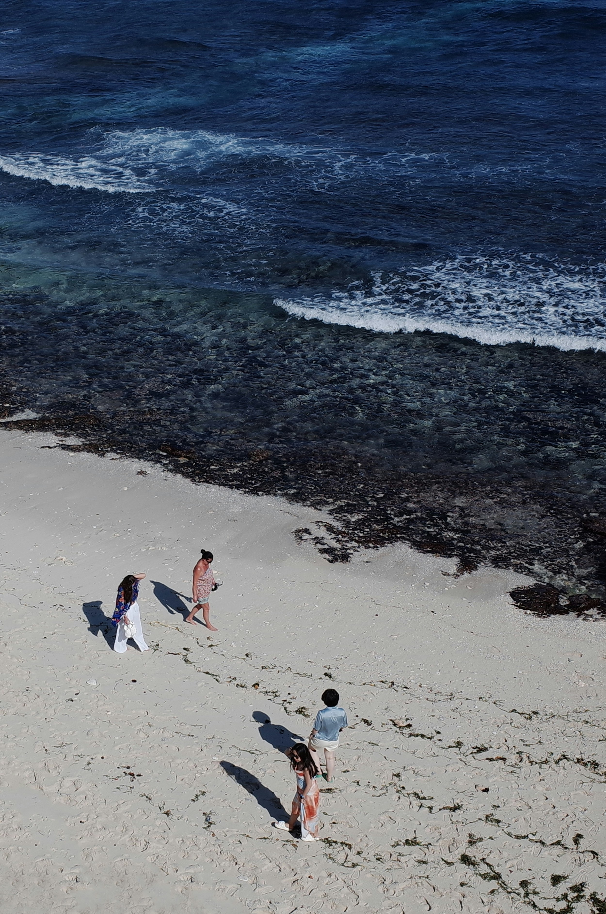 A group of people walking along a beach next to the ocean