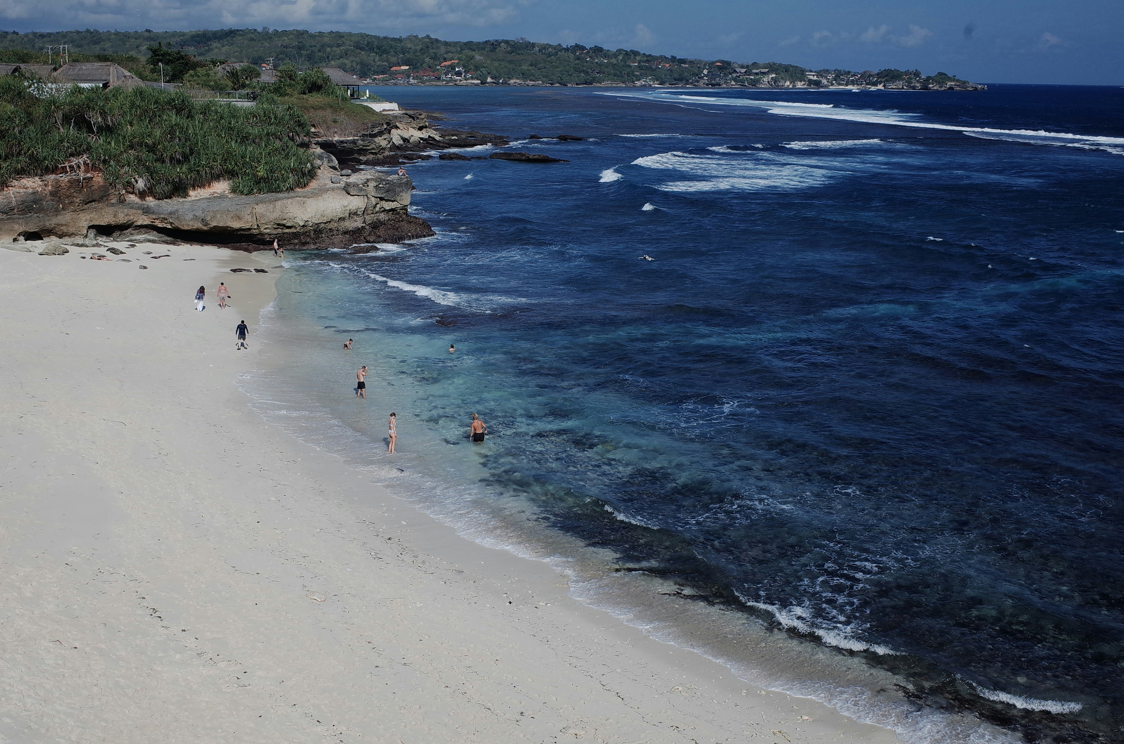 A beach with people walking on it next to the ocean