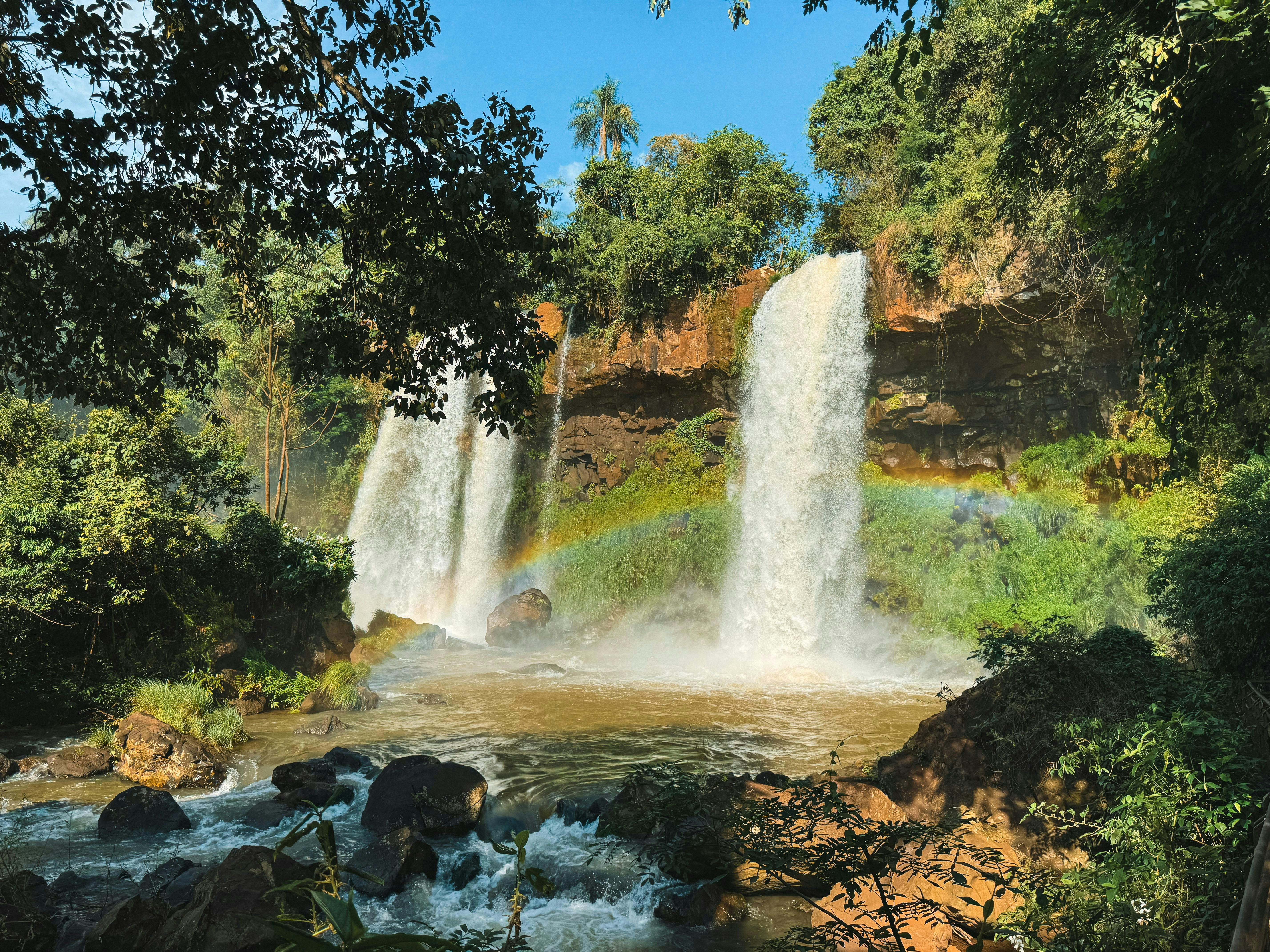 A waterfall with a rainbow in the middle of it, 