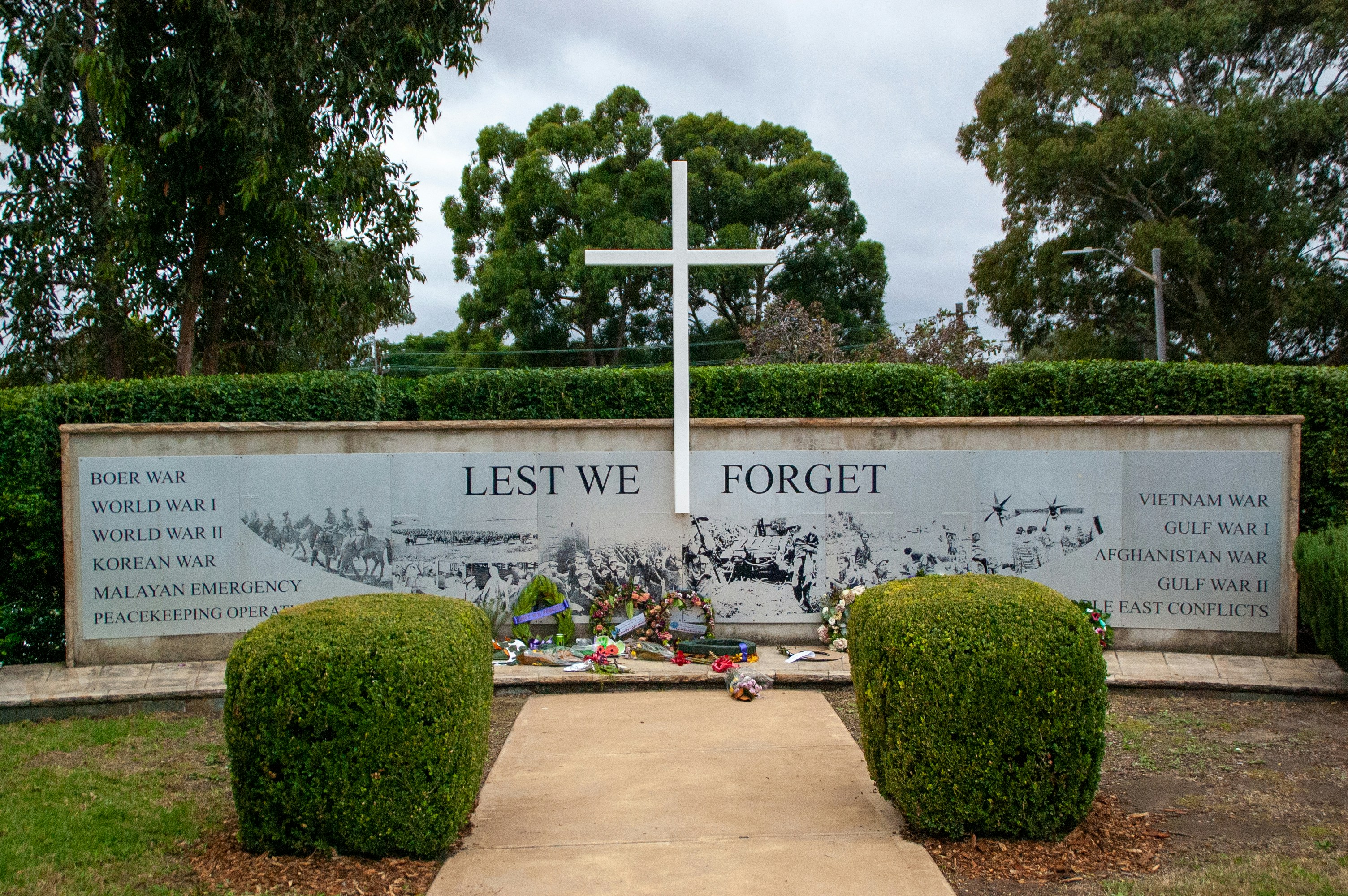 A white cross sitting on top of a lush green field