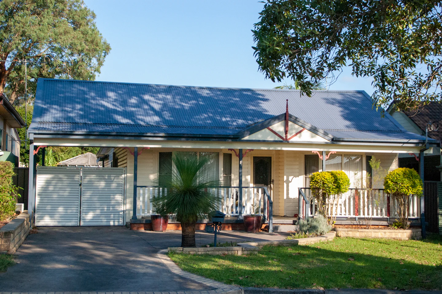 A weatherboard Australian bungalow with a verandah and a corrugated roof