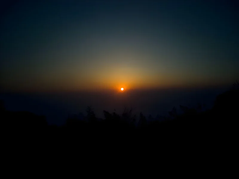 sun setting into a dark horizon