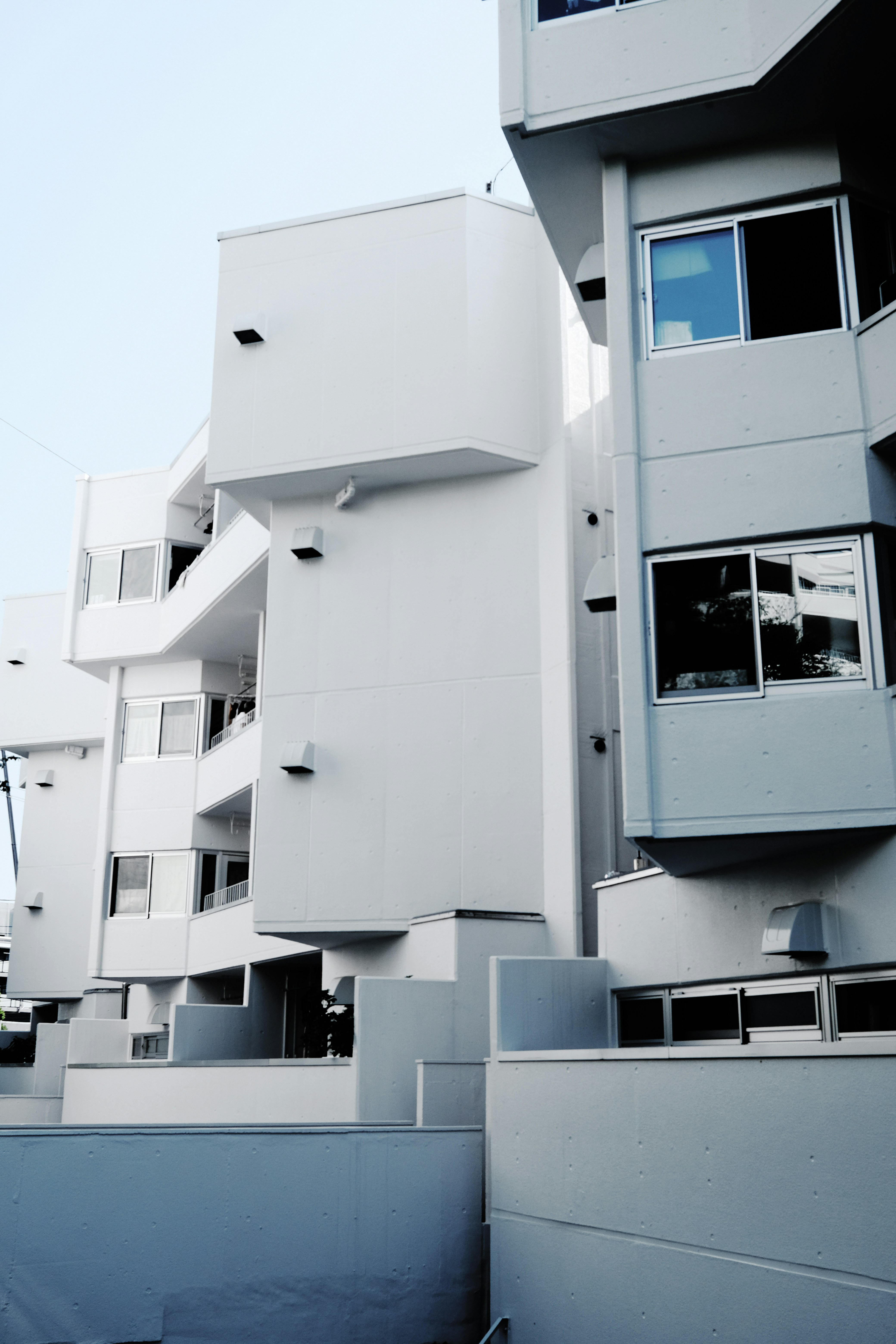 Modern multi-story building featuring modular white concrete facades and balconies.