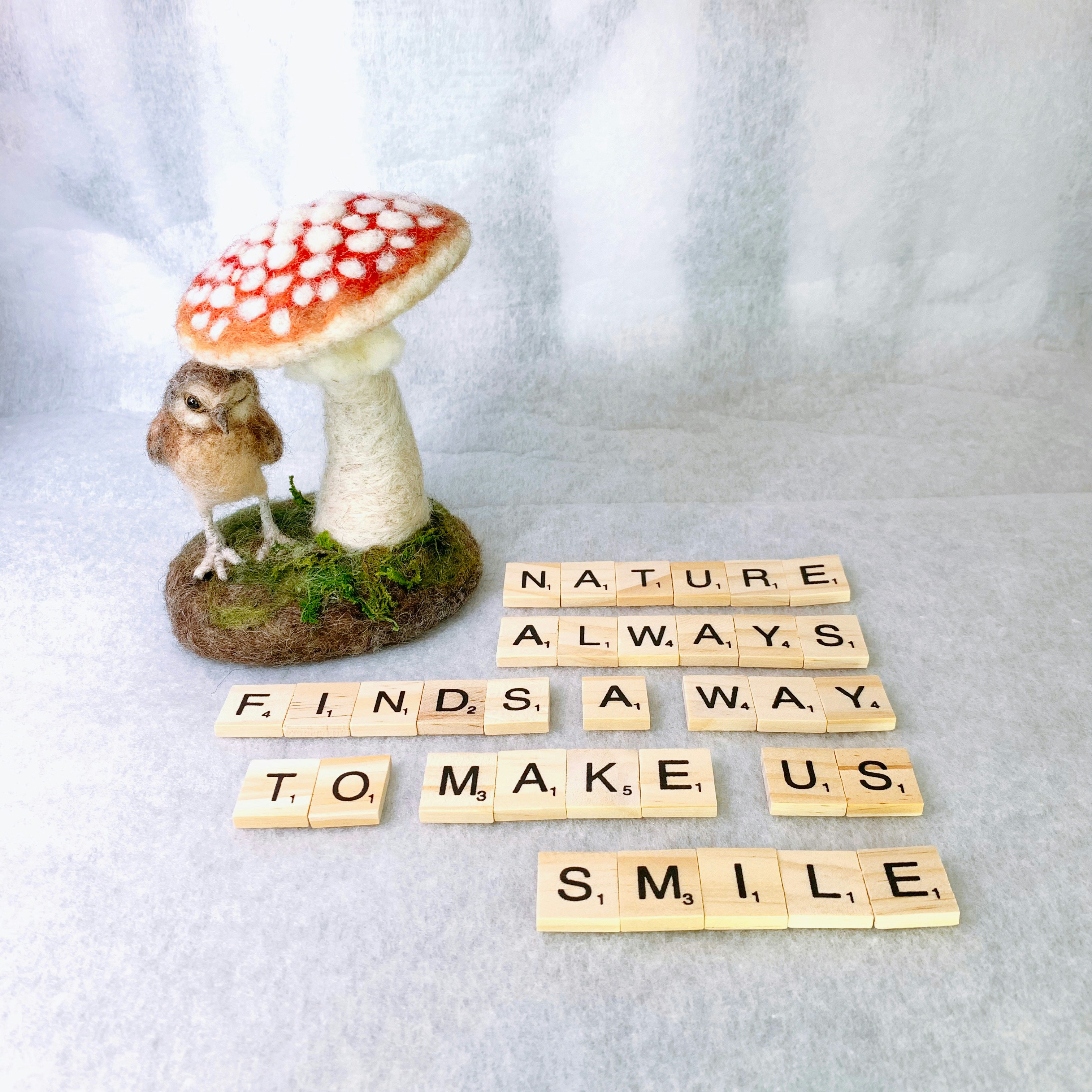 A small mushroom sitting next to scrabble tiles