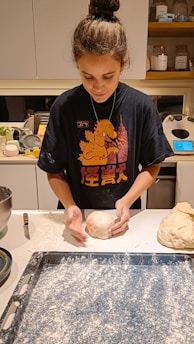 A woman is kneading dough in a kitchen