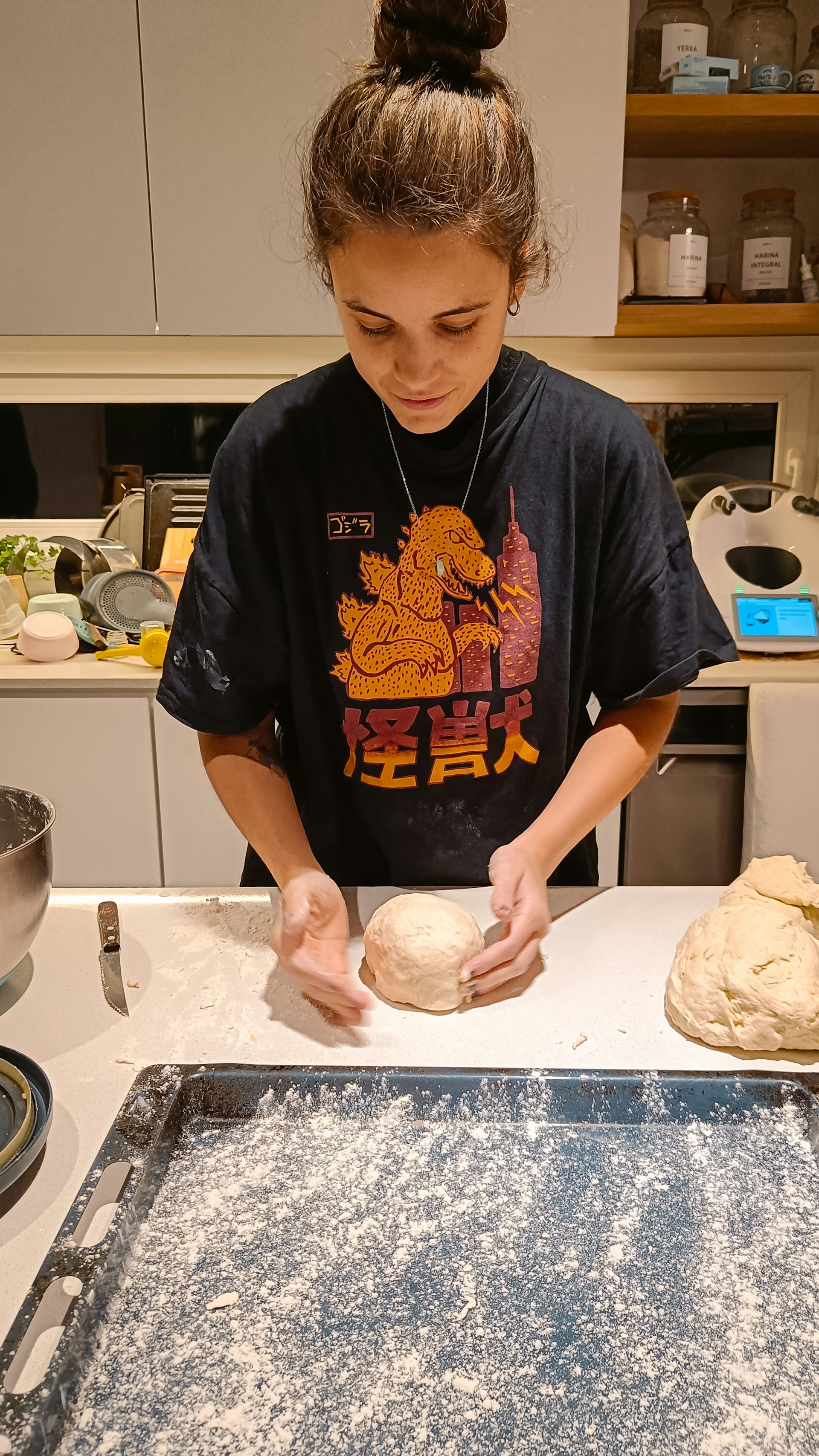 A woman is kneading dough in a kitchen