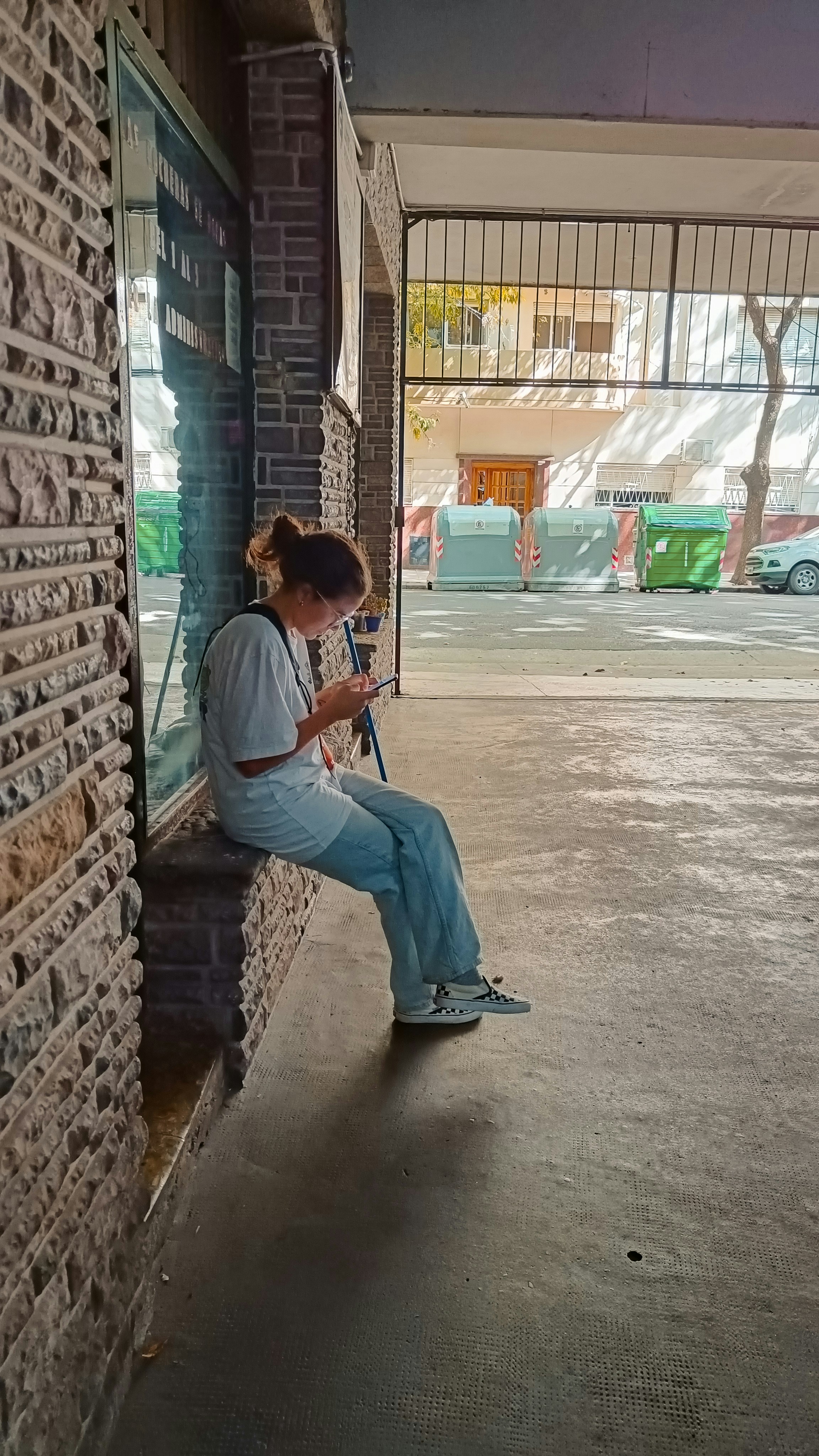 A woman sitting on a brick wall looking at her cell phone