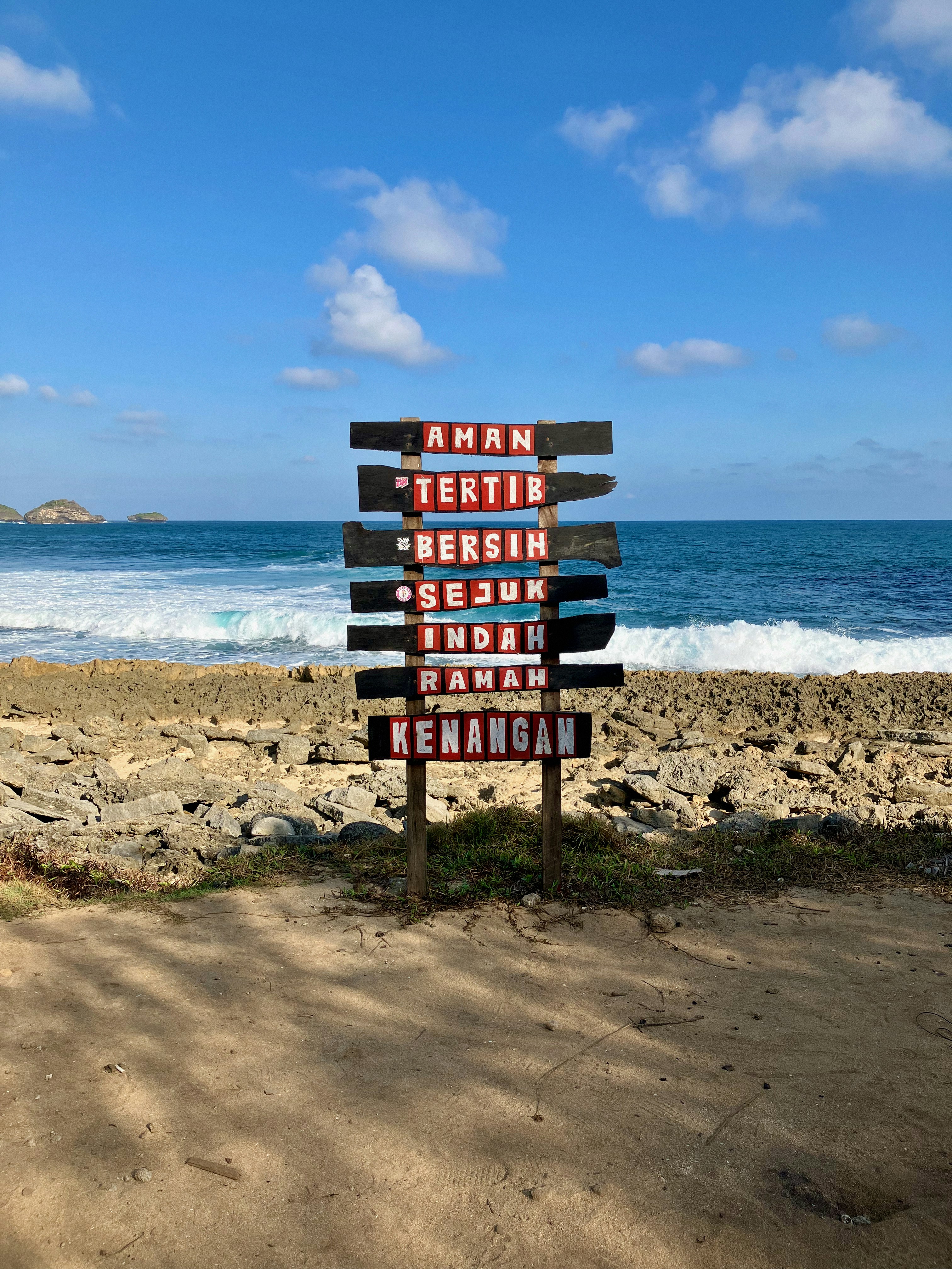 A wooden sign sitting on top of a sandy beach