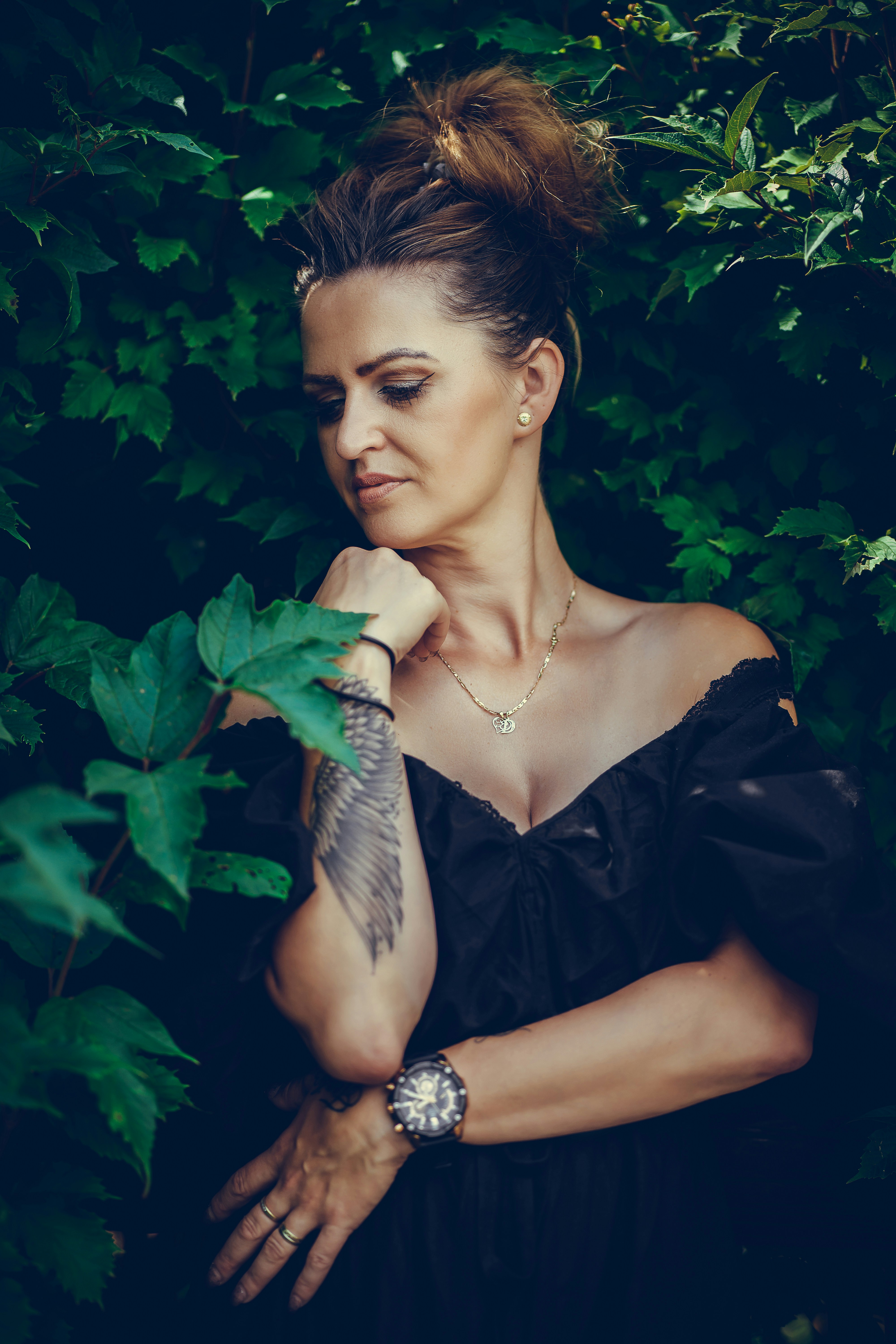 A woman in a black dress standing in front of a bush