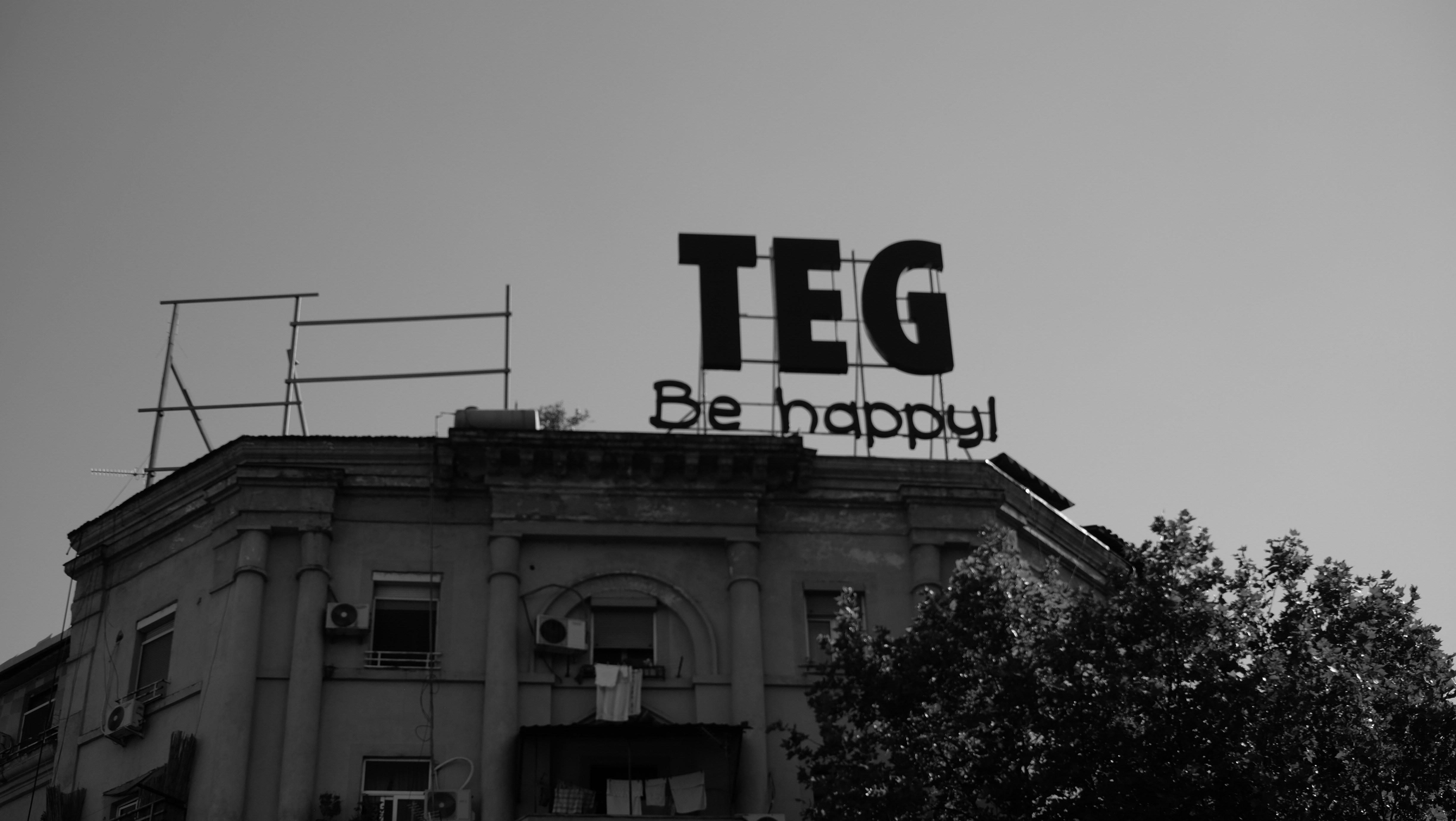 A black and white photo of a building with a sign on top
