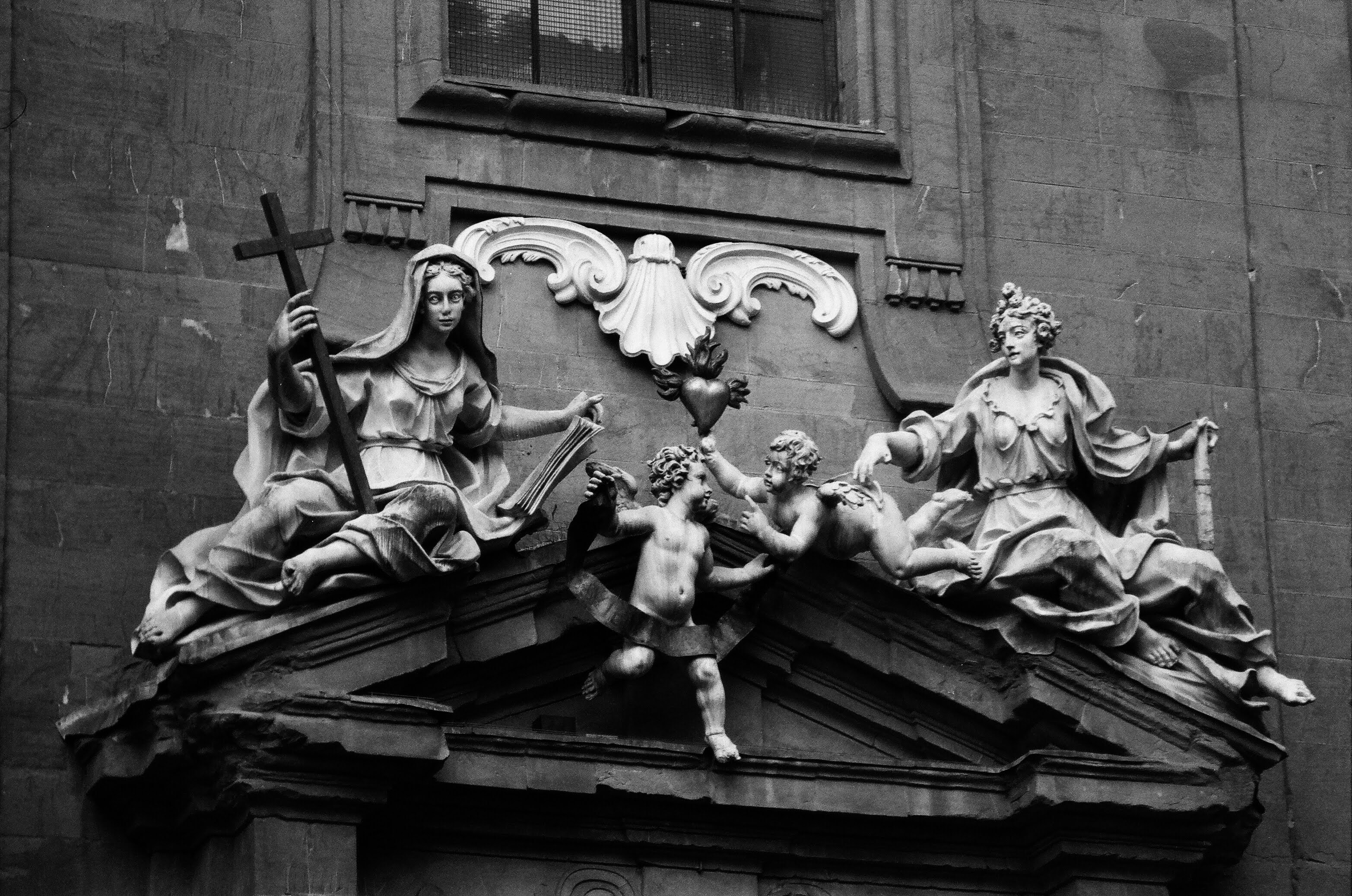A black and white photo of statues on the side of a building