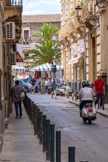 A man riding a motorcycle down a street next to tall buildings