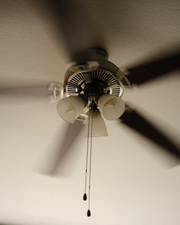 A spinning ceiling fan with 3 bulbs that is hanging from a ceiling