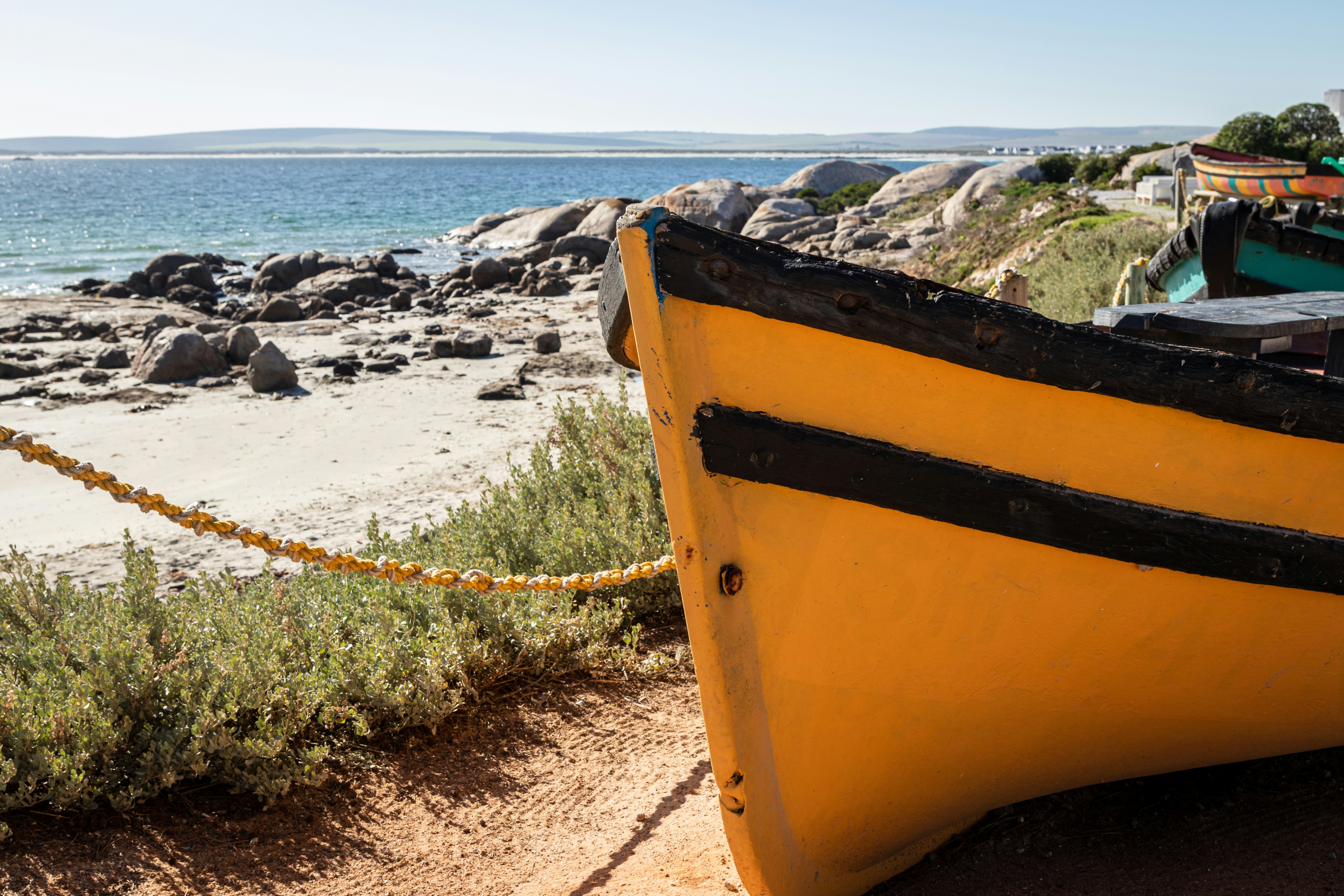A yellow boat sitting on top of a sandy beach, 