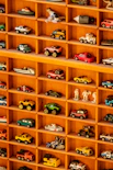 A wooden shelf filled with lots of toy cars