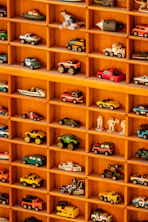 A wooden shelf filled with lots of toy cars