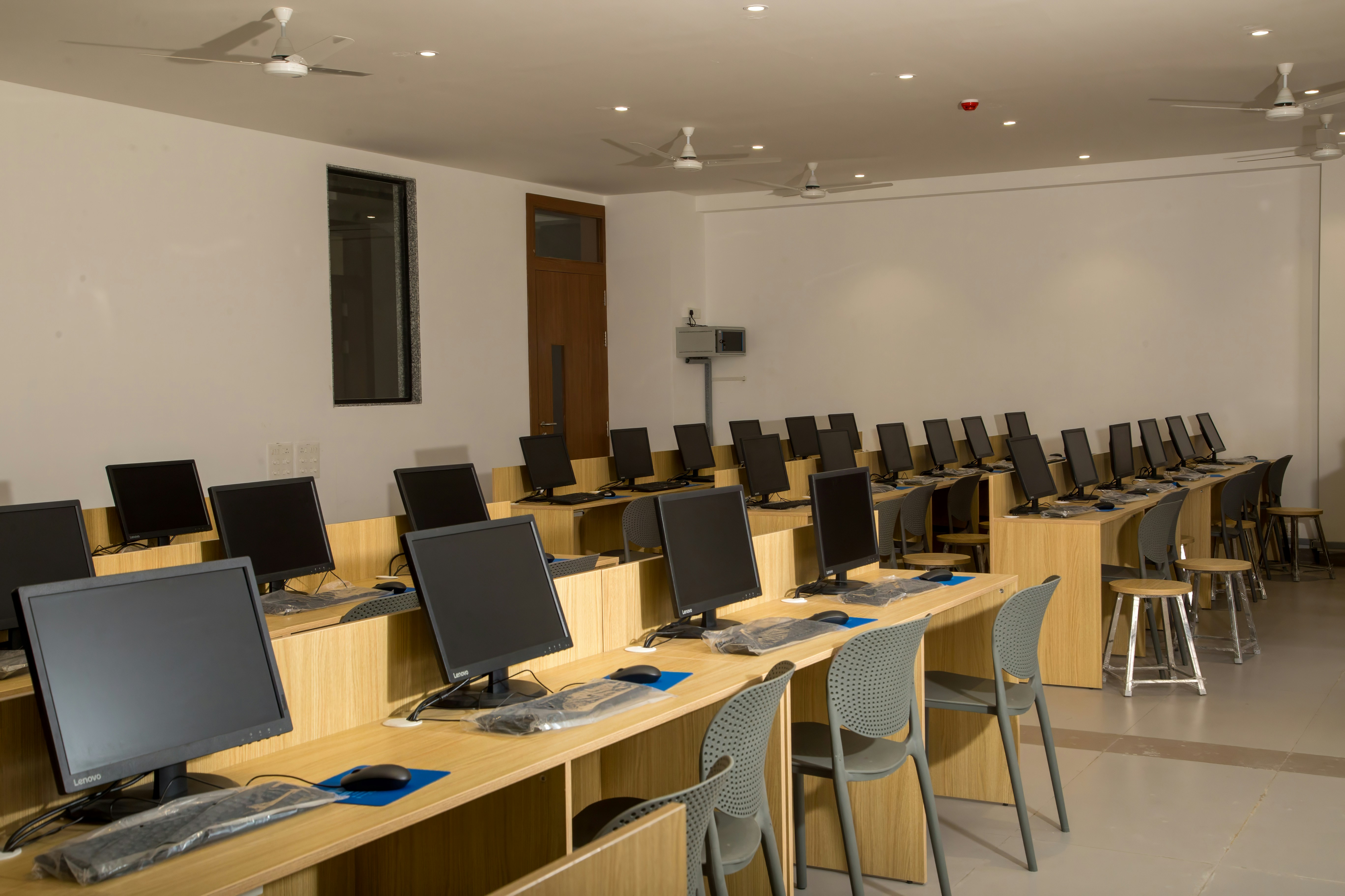 Professional computer testing centre with rows of secure workstations, controlled lighting and CCTV cameras, clean modern environment