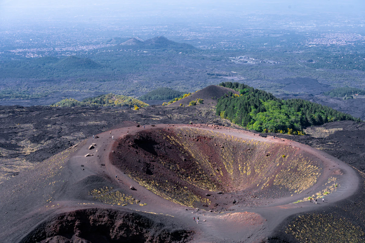 Aerial view of a volcanic summit crater with steam and bare rock