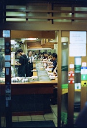 A group of people standing in a kitchen preparing food