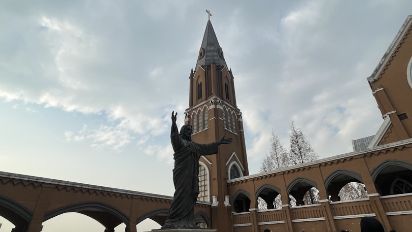 A large building with a clock tower and a statue in front of it