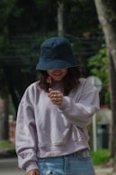 A woman in a blue hat is looking at her cell phone