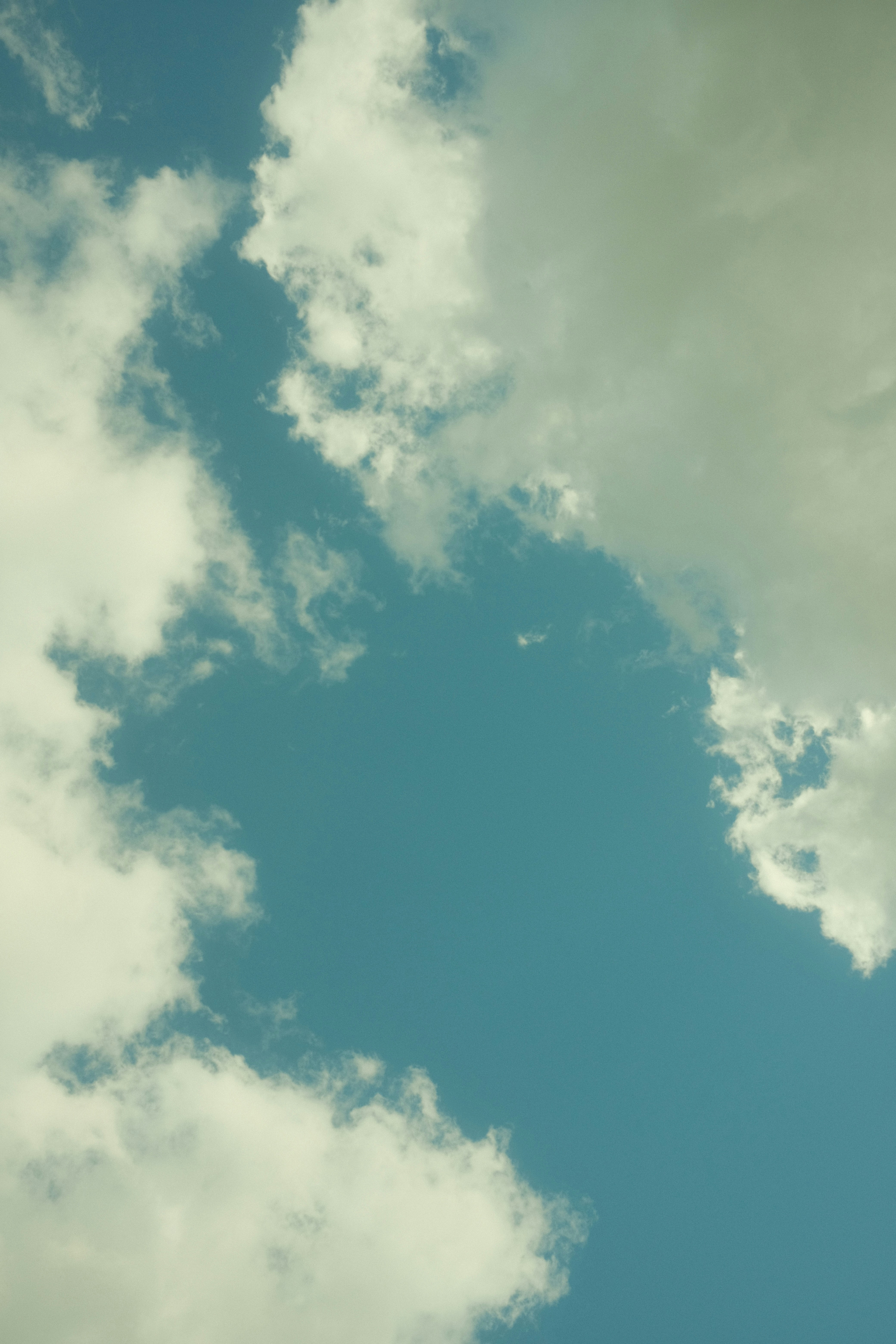 A plane flying through a cloudy blue sky