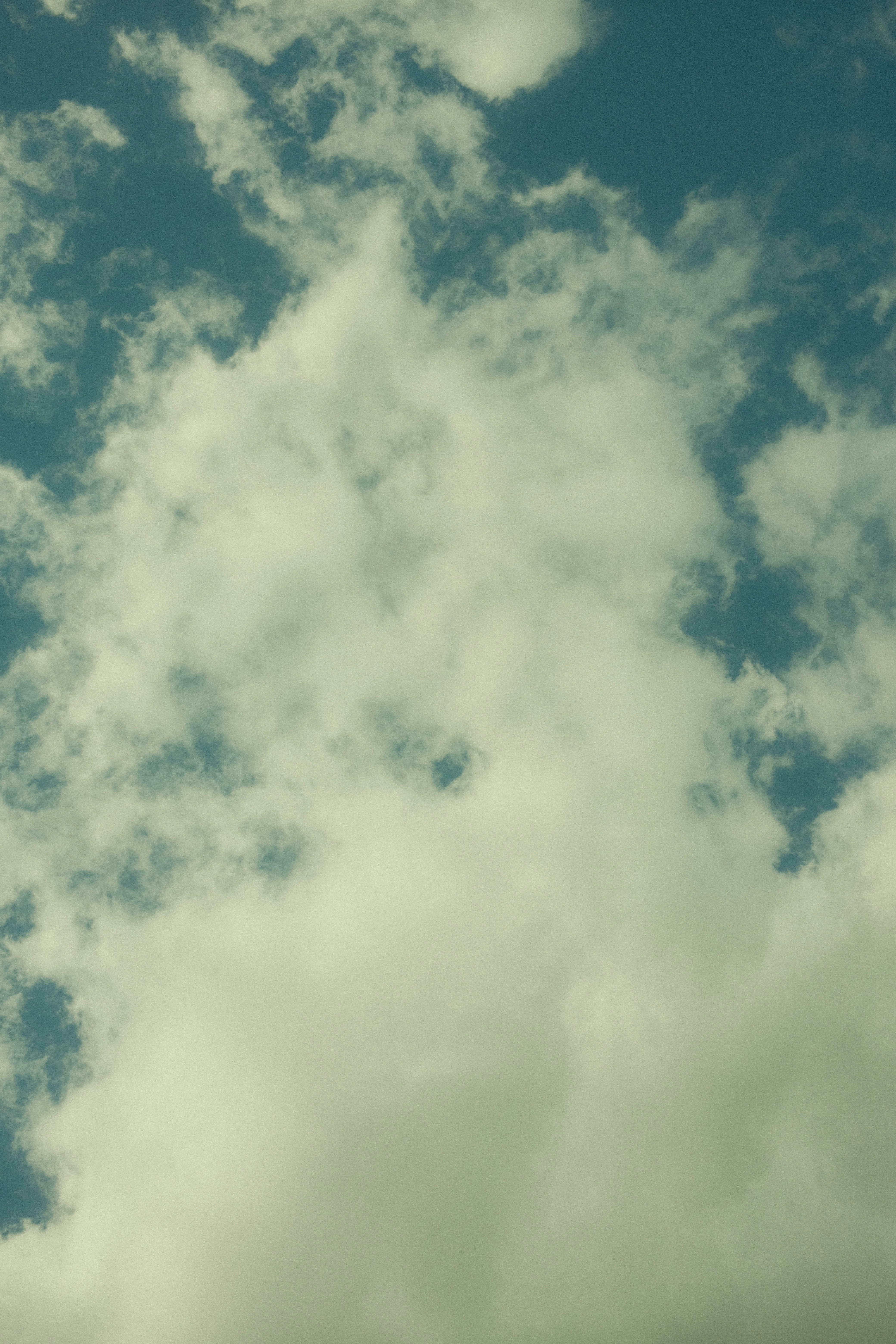 A plane flying through a cloudy blue sky