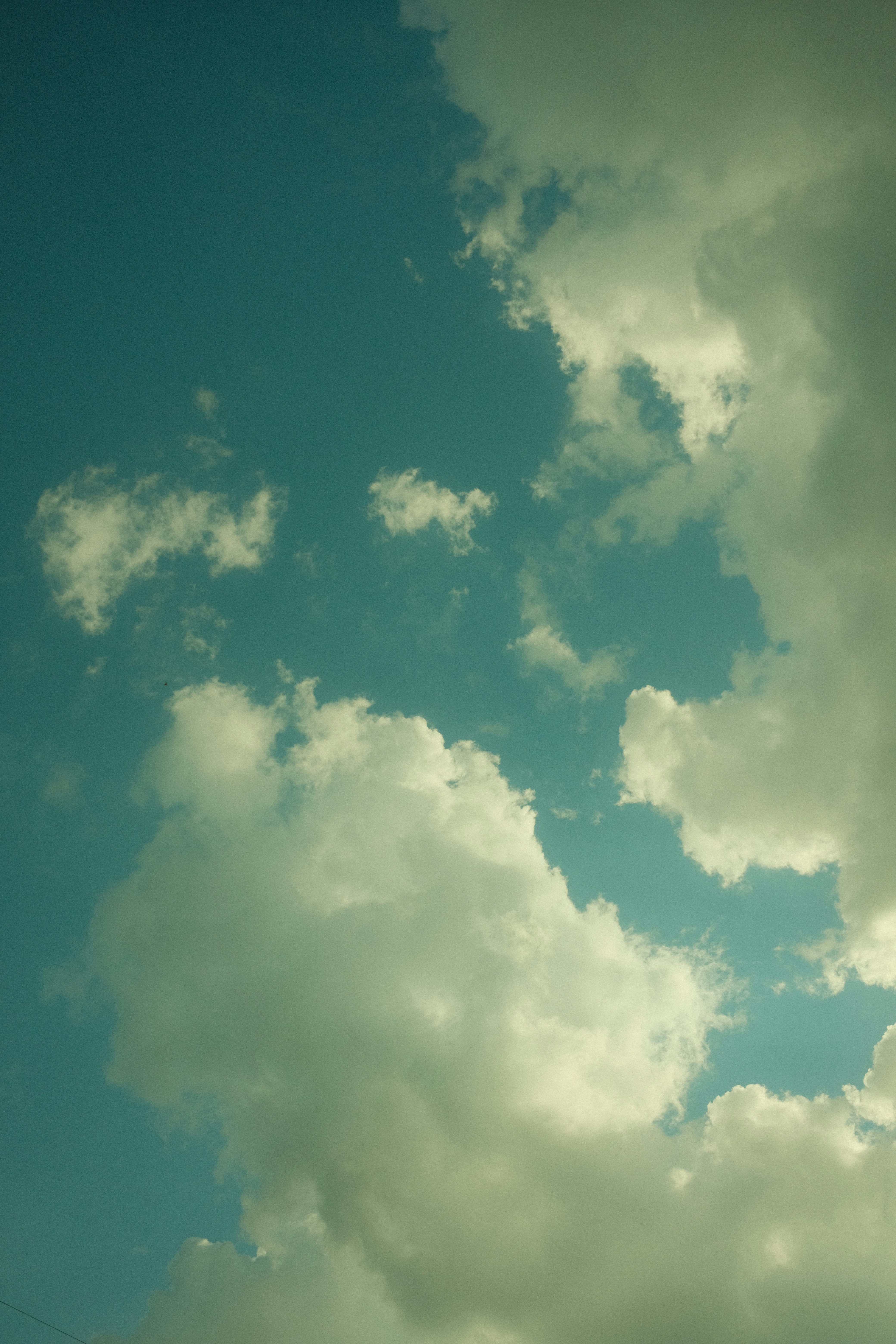 A plane flying through a cloudy blue sky