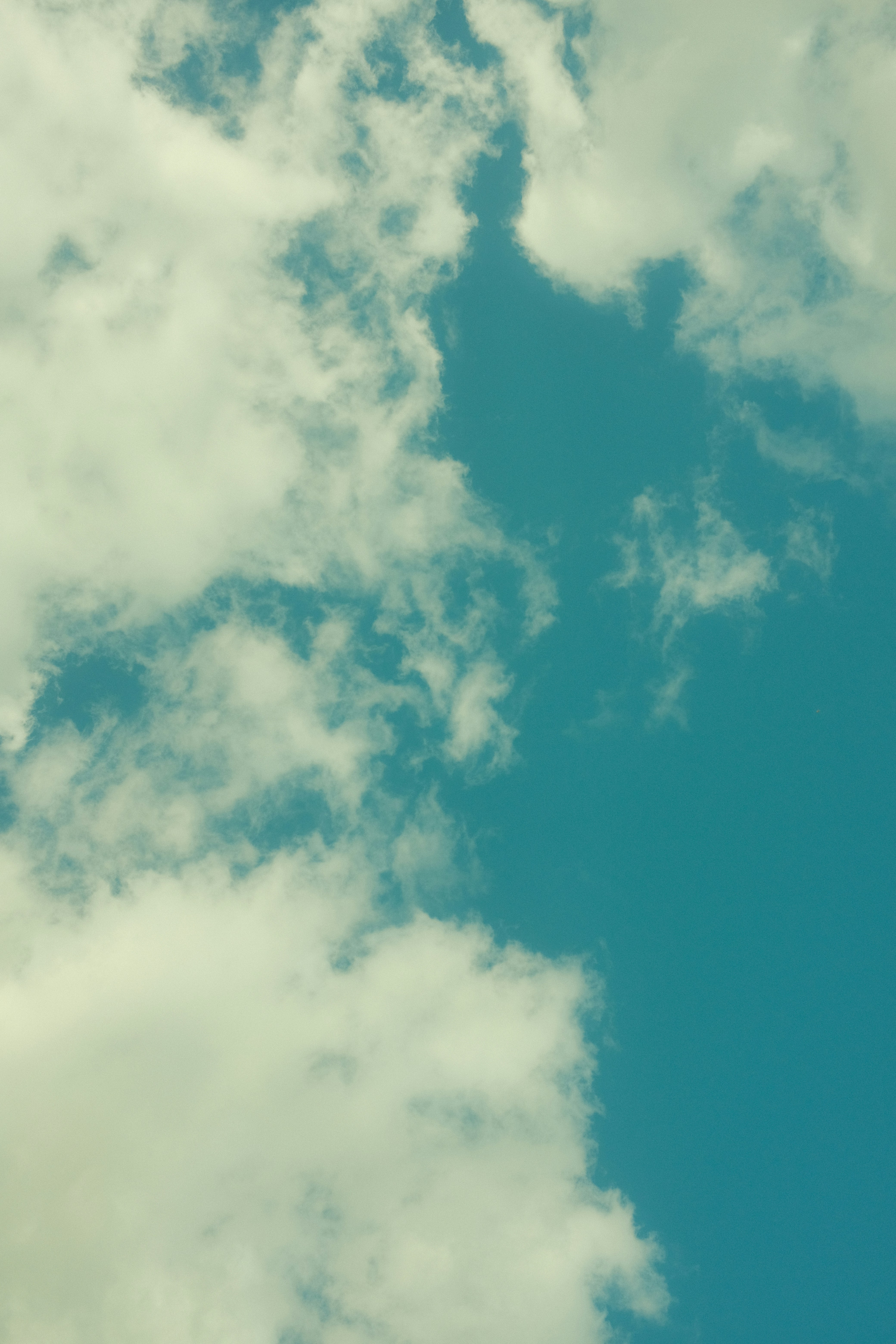 A plane flying through a cloudy blue sky