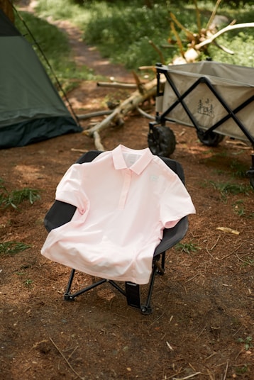 A pink polo supima cotton T-shirt sitting on top of a folding chair