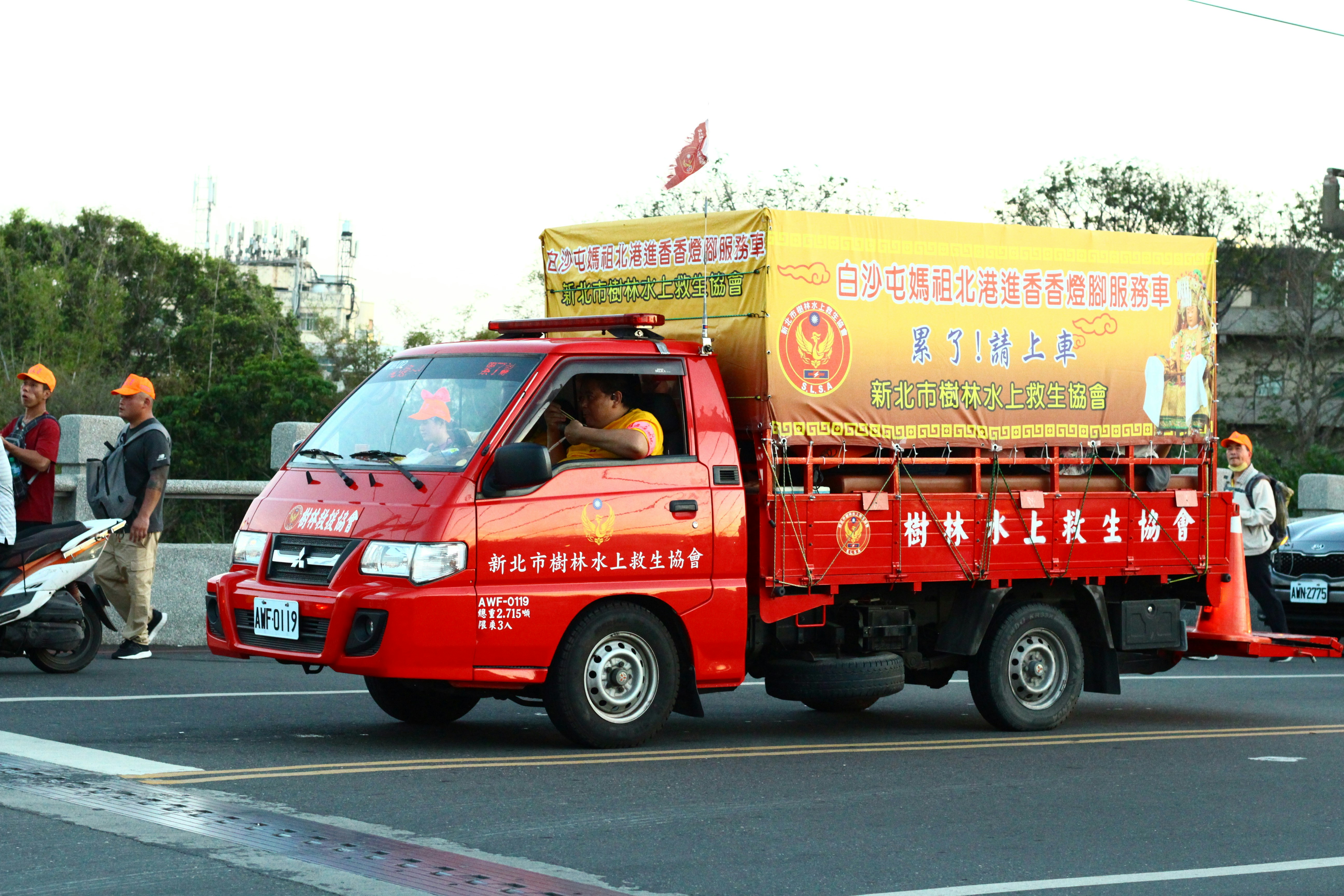 A red and yellow truck driving down a street