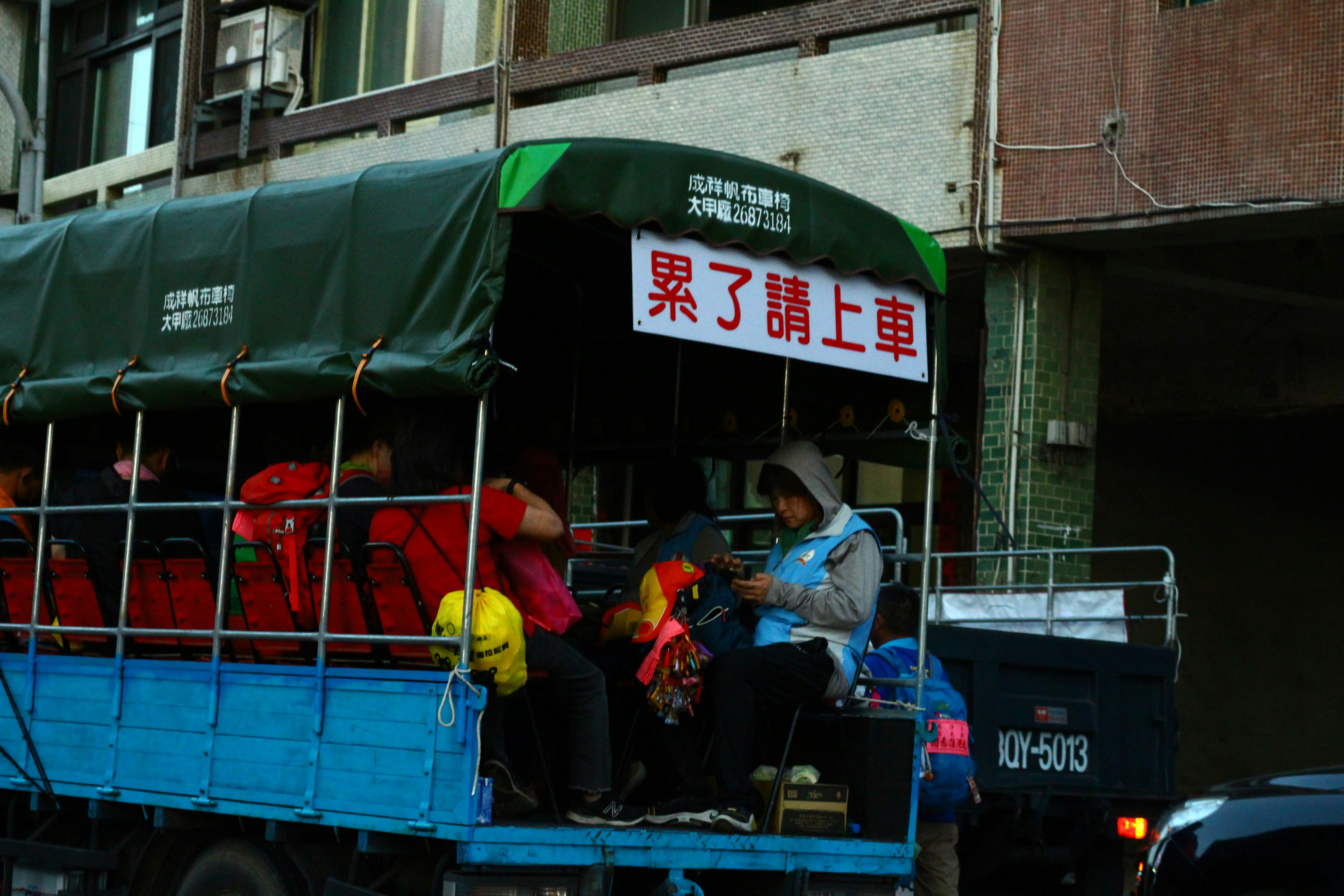 A group of people riding on the back of a blue truck