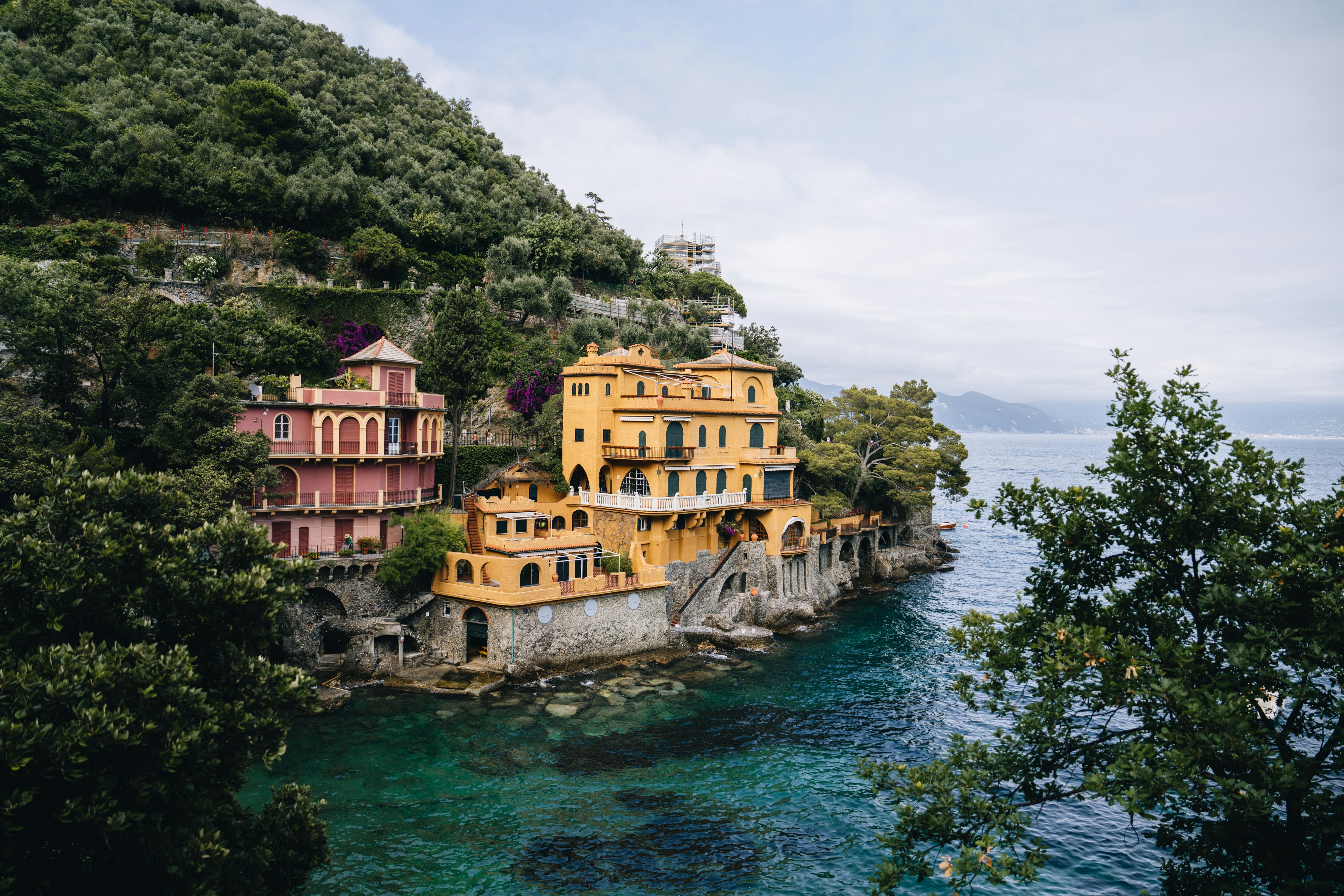 A group of buildings sitting on top of a cliff next to the ocean, 
