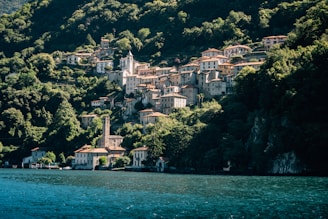A small village on the side of a mountain next to a body of water