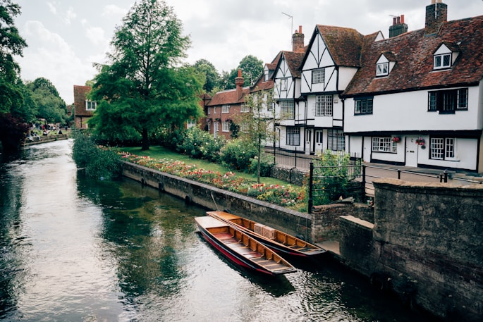A boat floating down a river next to a row of houses