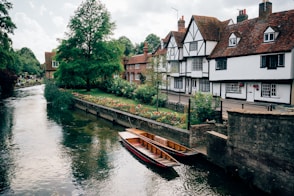 A boat floating down a river next to a row of houses