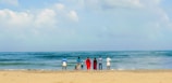 A group of people standing on top of a sandy beach